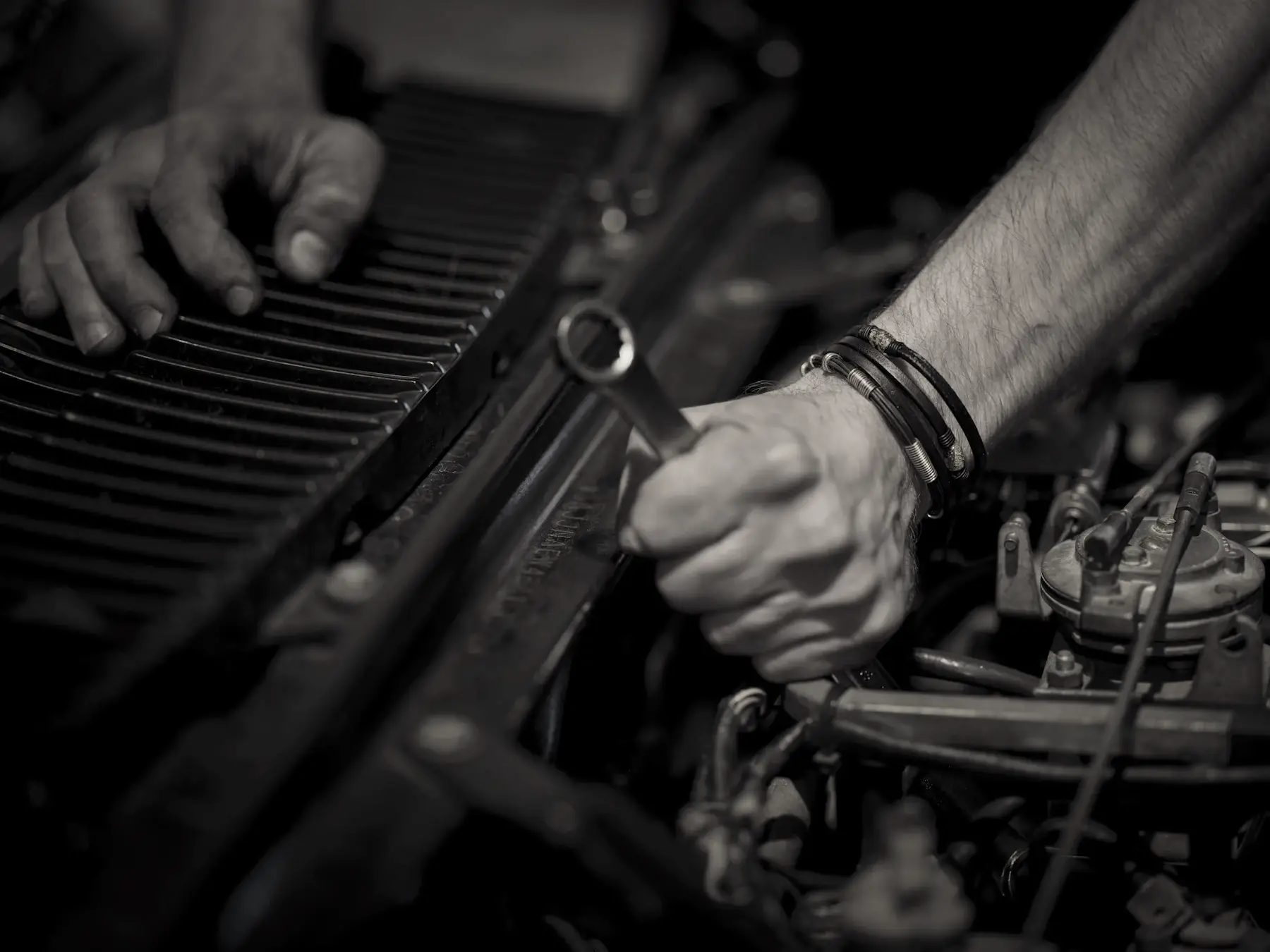 A mechanic's hands working on an engine with a wrench.