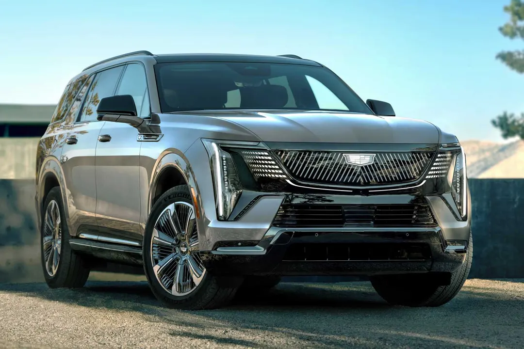 A silver Cadillac Escalade IQL electric SUV parked outdoors, seen from the front three-quarter angle