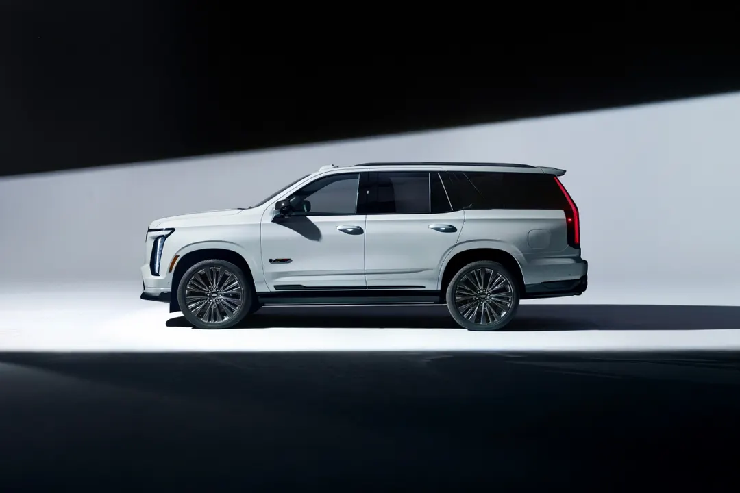 A white 2027 Cadillac Escalade-V 125th Anniversary Collector Series shown in side profile in a dark studio
