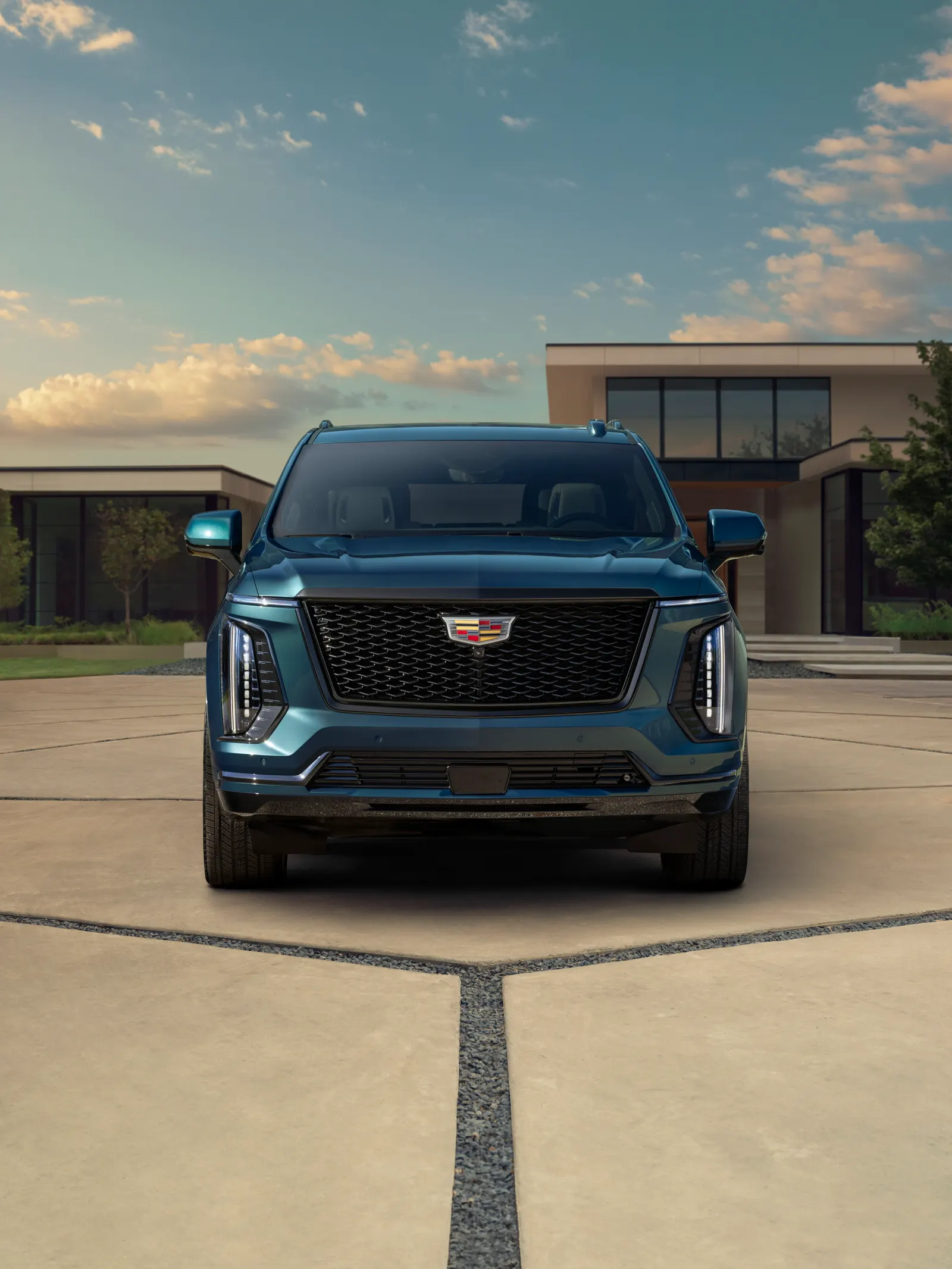 Front view of a dark blue 2025 Cadillac Escalade parked in front of a modern house