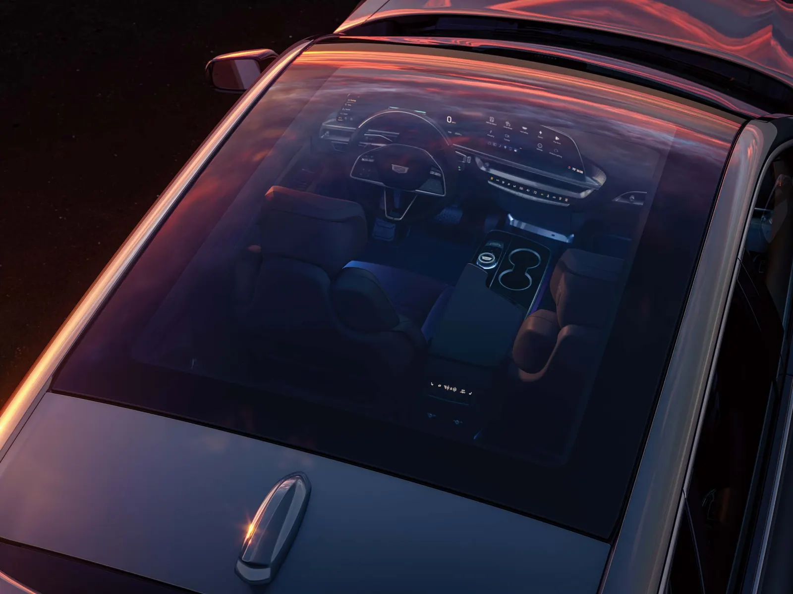 Overhead view through the glass roof of a 2027 Cadillac Lyriq at dusk, showing the steering wheel, curved dashboard display and center console